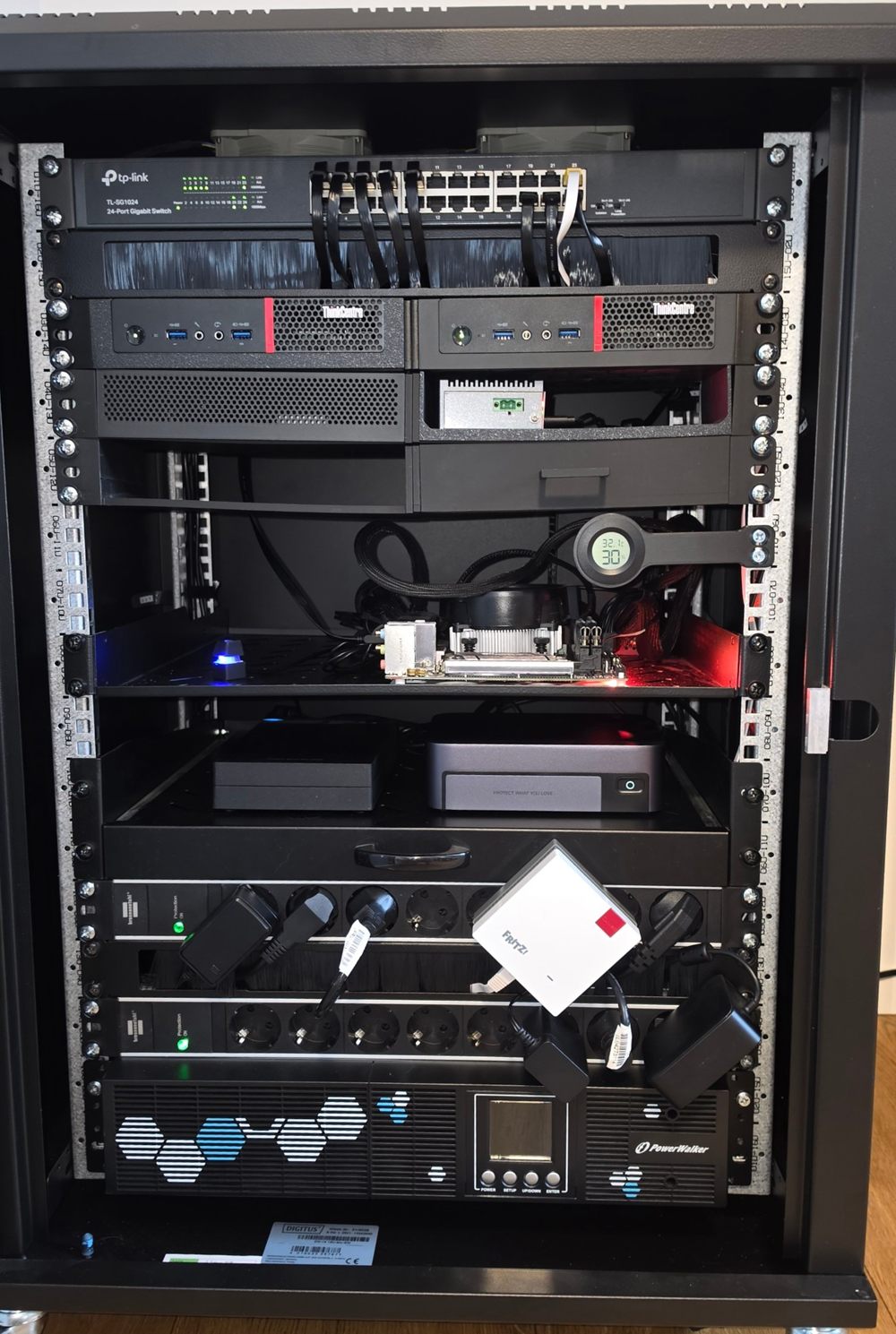 D’Rack mat Ventilatoren, Switch, zwee ThinkCentre, Raspberry Pi, engem Spillserver ouni Gehais, HDD, NAS, Steckdousen, FRITZ! an UPS